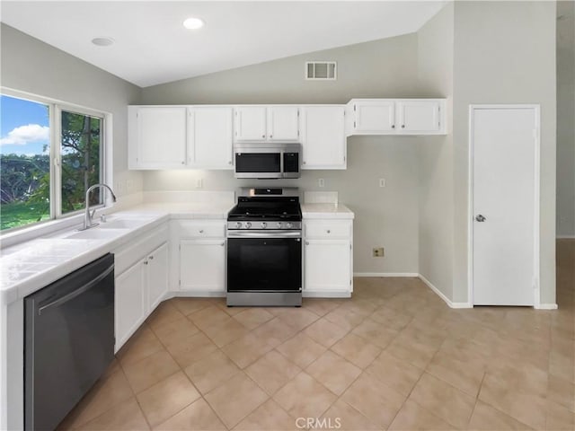 kitchen featuring a sink, visible vents, stainless steel appliances, tile countertops, and vaulted ceiling