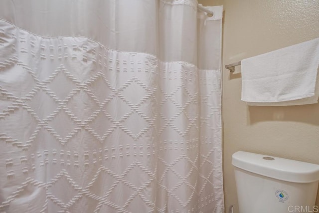 full bath with toilet and a shower with shower curtain