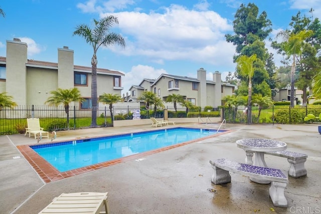 pool with a residential view, fence, and a patio