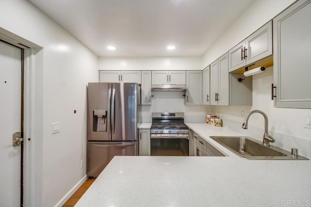 kitchen with gray cabinets, dark wood-style flooring, appliances with stainless steel finishes, a sink, and under cabinet range hood