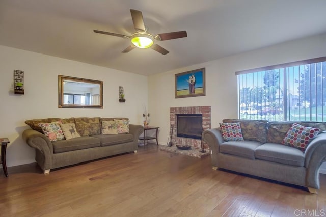 living room with baseboards, ceiling fan, wood finished floors, and a fireplace