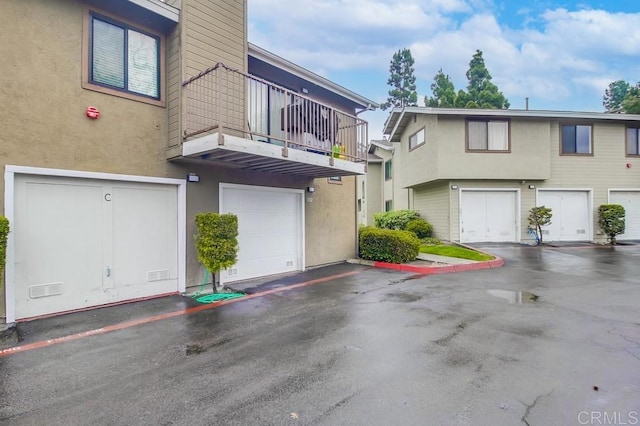 exterior space featuring a garage, stucco siding, and a balcony