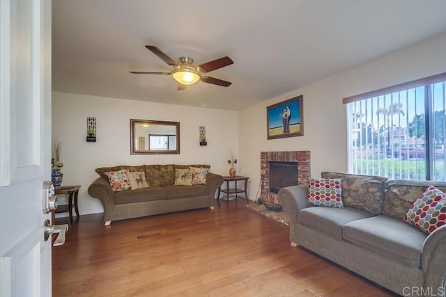living room featuring ceiling fan, light wood-style flooring, and a fireplace