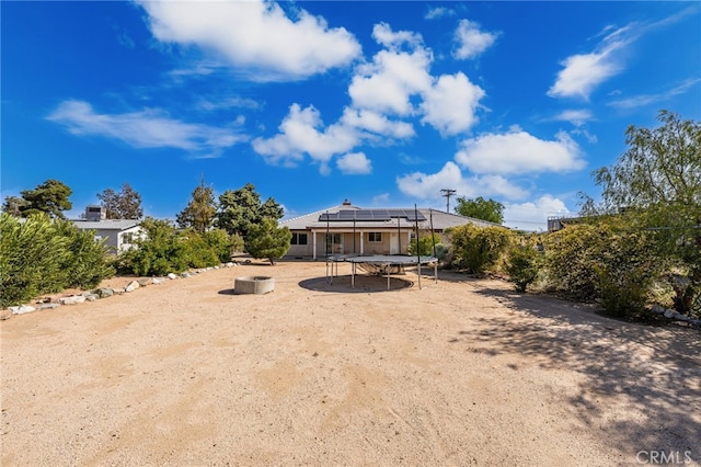 back of property with a trampoline and roof mounted solar panels