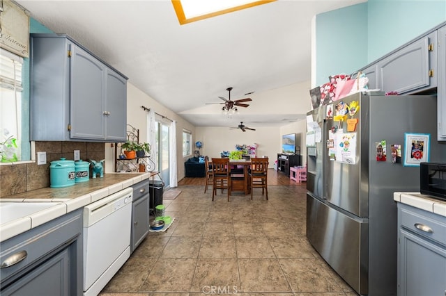 kitchen with black microwave, tile counters, freestanding refrigerator, and dishwasher