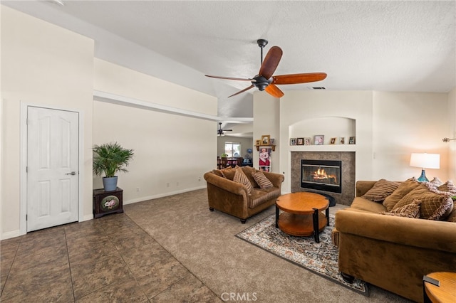 carpeted living room with a textured ceiling, ceiling fan, baseboards, and a tile fireplace