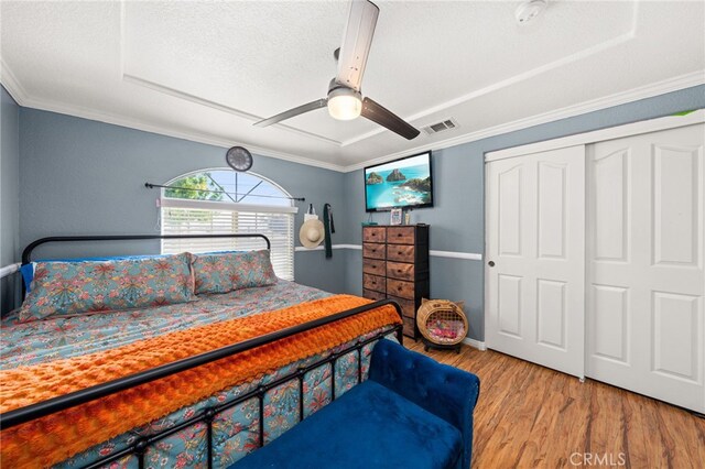 bedroom with visible vents, crown molding, a closet, wood finished floors, and a ceiling fan