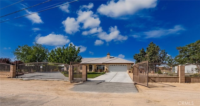 view of front of house with a chimney, a gate, a garage, fence, and concrete driveway