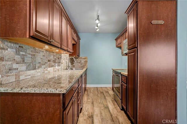 1130 E 1st St Unit 205, Long Beach, CA 90802 - kitchen featuring baseboards, tasteful backsplash, a sink, light wood-style flooring, and stainless steel appliances