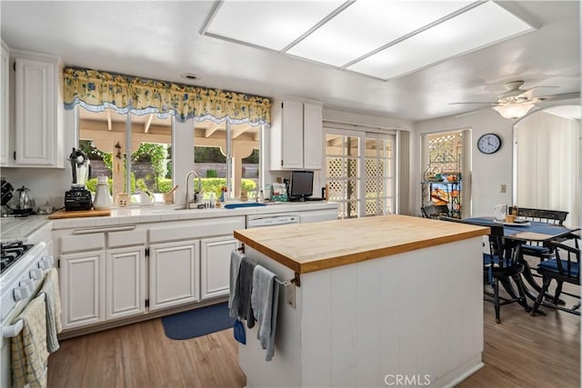 kitchen with white cabinets, wood counters, a wealth of natural light, and a sink