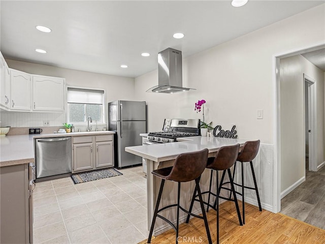 1234 N Pass Ave, Burbank, CA 91505 - kitchen with a peninsula, a breakfast bar, wall chimney exhaust hood, a sink, and stainless steel appliances