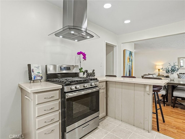 1234 N Pass Ave, Burbank, CA 91505 - kitchen with island range hood, stainless steel gas range oven, light countertops, a peninsula, and a breakfast bar