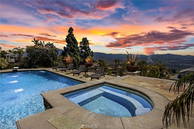 26930 Ironstone, Yorba Linda, CA 92887 - pool at dusk featuring an in-ground hot tub, an outdoor pool, a patio, and a mountain view