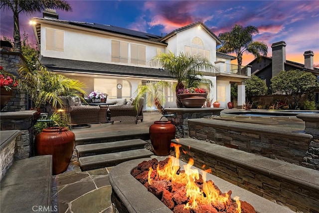 26930 Ironstone, Yorba Linda, CA 92887 - rear view of property featuring solar panels, a balcony, a hot tub, an outdoor living space with a fire pit, and stucco siding