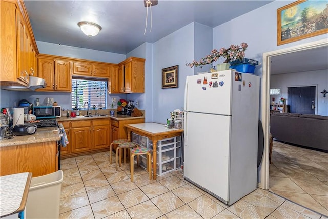 kitchen with brown cabinets, appliances with stainless steel finishes, ventilation hood, a sink, and light countertops