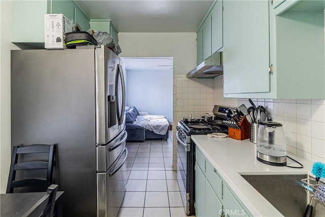 kitchen featuring a sink, stainless steel appliances, decorative backsplash, light tile patterned floors, and under cabinet range hood