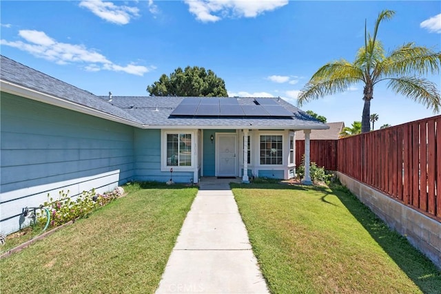 view of front facade featuring solar panels and roof with shingles