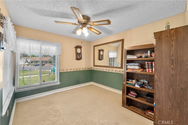 carpeted spare room with a ceiling fan, a textured ceiling, and baseboards