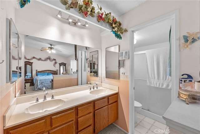 ensuite bathroom featuring double vanity, a stall shower, ceiling fan, and toilet