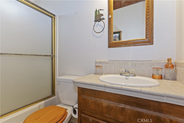 bathroom featuring vanity, a shower with shower door, and toilet