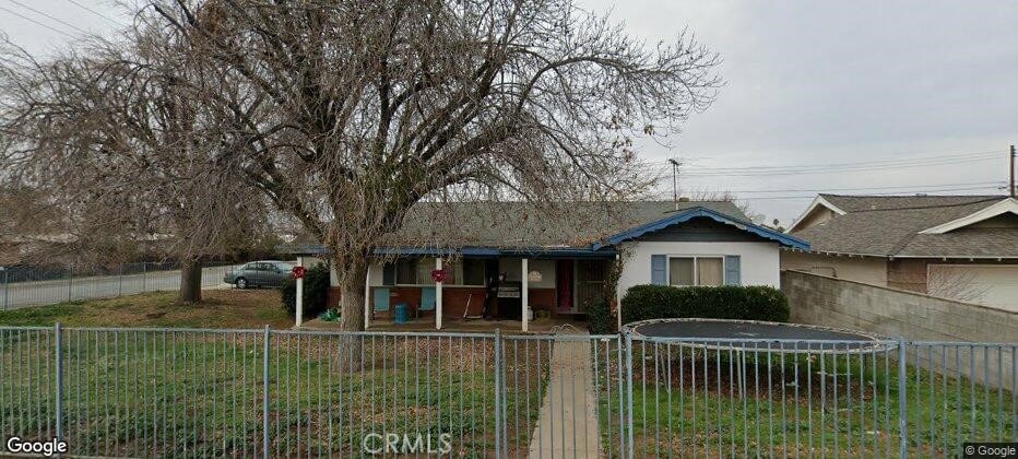 view of front of property with a trampoline, stucco siding, and fence private yard