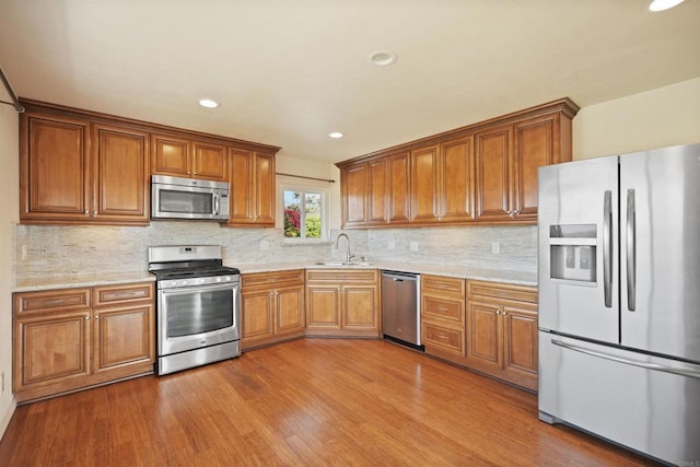5884 Redondo Dr, Bonsall, CA 92003 - kitchen with appliances with stainless steel finishes, a sink, brown cabinets, wood finished floors, and recessed lighting