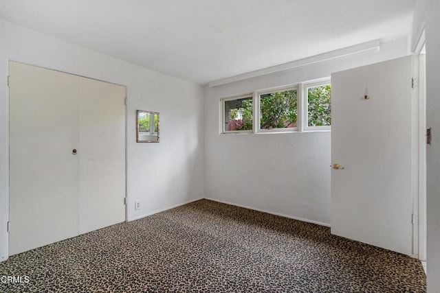 unfurnished bedroom featuring multiple windows, carpet, and a closet