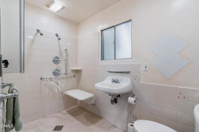 full bathroom featuring a tile shower, toilet, and tile walls