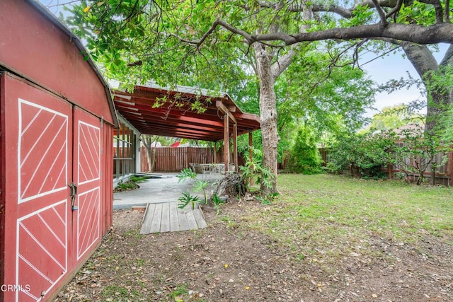 view of yard featuring an outbuilding, a fenced backyard, and a patio area