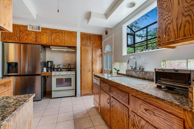 kitchen featuring visible vents, white range with gas stovetop, stainless steel fridge, under cabinet range hood, and a sink
