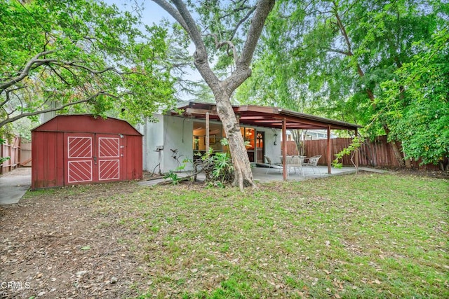 back of property with a lawn, an outdoor structure, a fenced backyard, a storage unit, and a patio