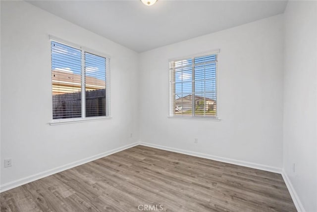 empty room featuring plenty of natural light, baseboards, and wood finished floors