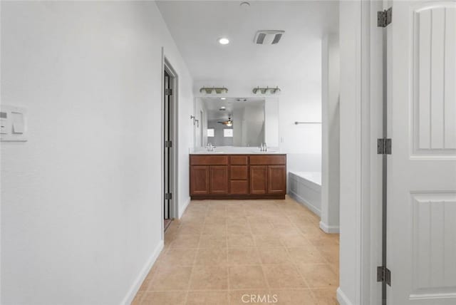 full bathroom featuring double vanity, baseboards, recessed lighting, a bath, and a sink