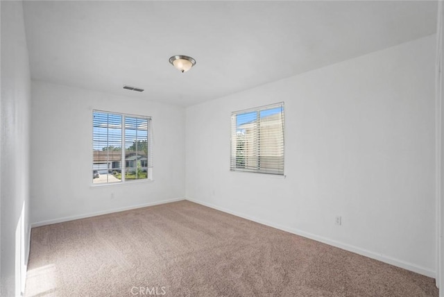 empty room with carpet flooring, baseboards, and visible vents