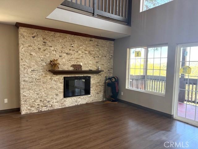 373 Davos Dr, Crestline, CA 92325 - unfurnished living room with a large fireplace, baseboards, wood finished floors, and a high ceiling