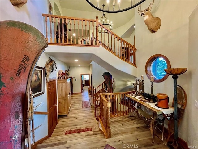 staircase featuring wood finished floors, a high ceiling, and an inviting chandelier