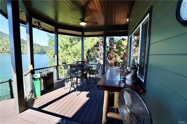 wooden terrace featuring a water view, a ceiling fan, and outdoor dining area