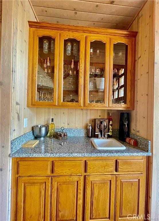 bar with a sink, wet bar, wooden walls, and wooden ceiling