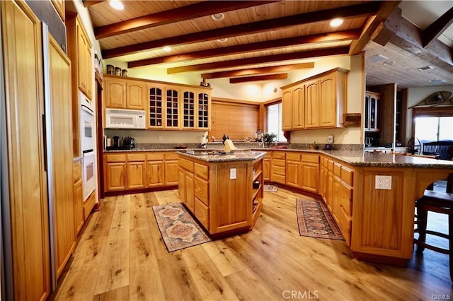 kitchen featuring a peninsula, white appliances, a breakfast bar area, wooden ceiling, and light wood finished floors