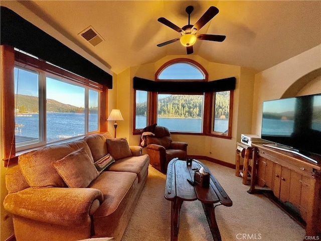 living room with a wealth of natural light, ceiling fan, vaulted ceiling, and visible vents