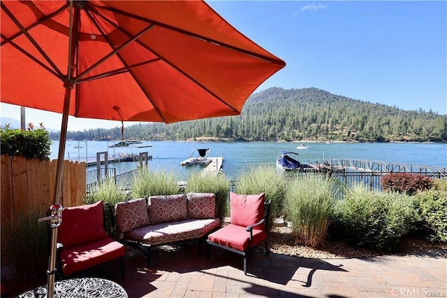 view of patio / terrace featuring a forest view, fence, and a water view