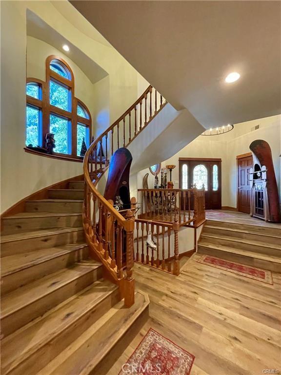 stairway with a high ceiling, recessed lighting, wood finished floors, and visible vents
