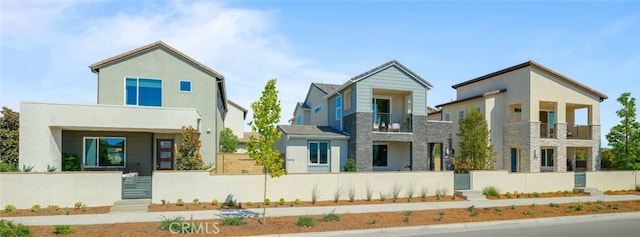 exterior space with a fenced front yard, a balcony, and stucco siding
