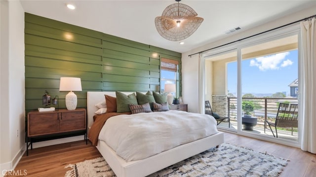 bedroom featuring visible vents, wood finished floors, multiple windows, and access to exterior