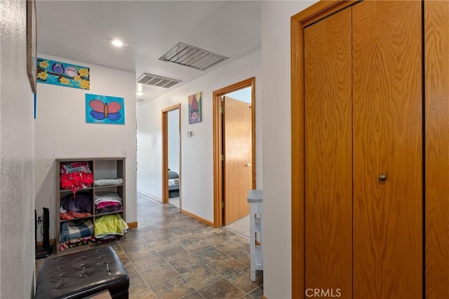 hallway with baseboards, visible vents, and stone finish floor