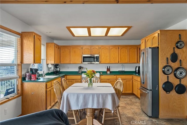 kitchen with a sink, brown cabinets, dark countertops, and stainless steel appliances
