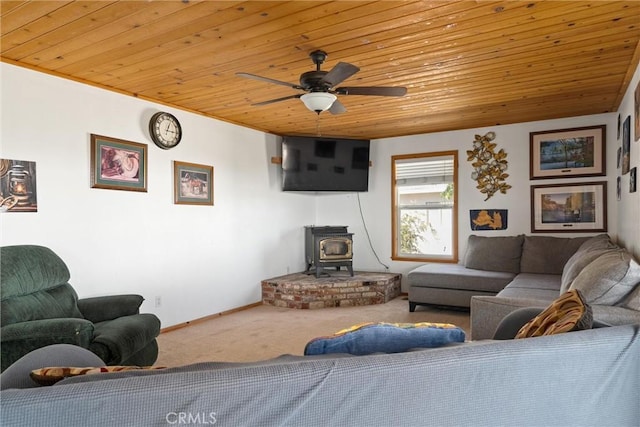 living room featuring a wood stove, baseboards, ceiling fan, wood ceiling, and carpet flooring