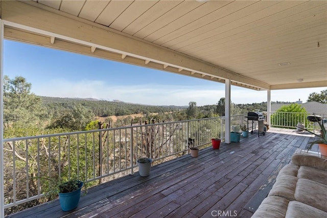 wooden terrace featuring grilling area and a forest view