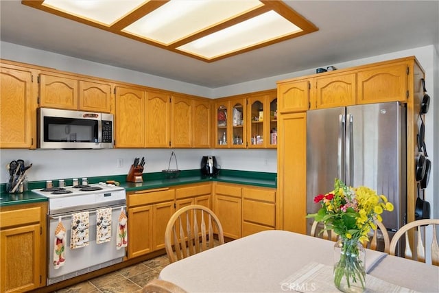kitchen featuring stainless steel appliances, brown cabinetry, and glass insert cabinets