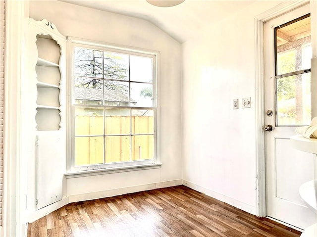 doorway featuring baseboards, vaulted ceiling, and wood finished floors